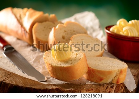 Bread and butter. Sliced French bread baguette with butter curls and knife.