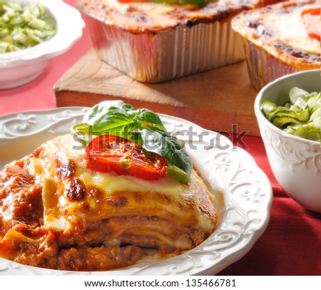 Beef lasagna on dish with cucumber salad as side dish