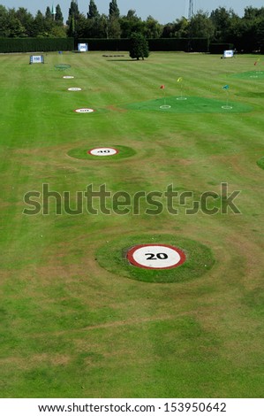 Golf driving range outdoors with distance markers.