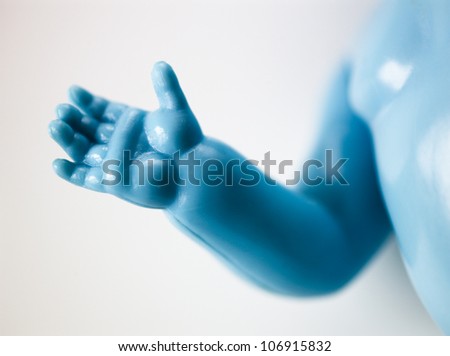 The hand of a blue plastic doll. close-up.