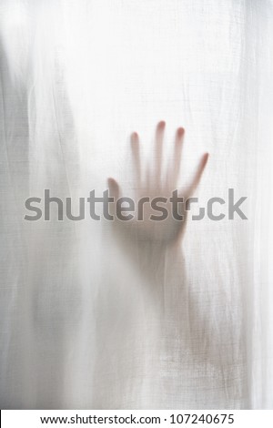 Human hand behind curtain