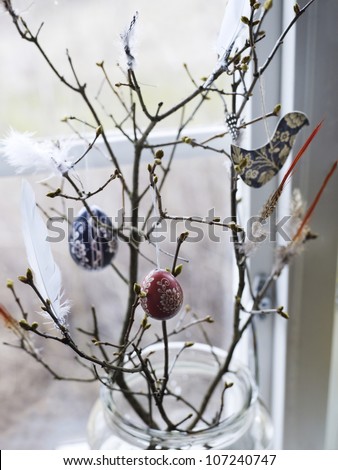 Feather and decorations hanging on bare branches