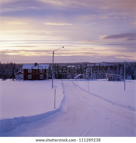 Snow-covered road leading towards house, Sweden