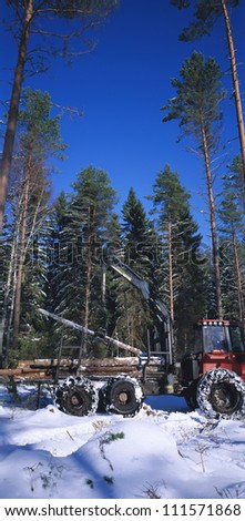 Tractor hauling tree trunks in a winter forest