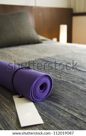 A carpet prepared for yoga classes on a bed