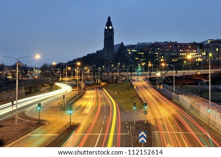 View of empty road at night with church and cityscape in background