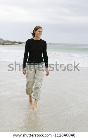 A smiling woman walking along the beach, Norway.