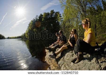 Four persons sitting by a lake, Sweden.