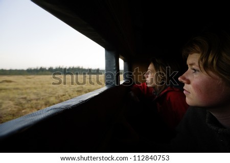 A woman taking pictures from a cabin window.