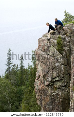 Two people sitting on a cliff, Ostergotland, Sweden.