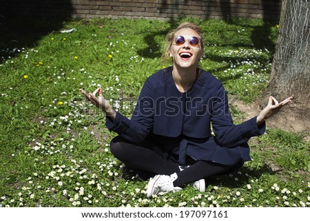 Happy young woman meditating on grass, United Kingdom