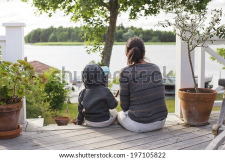 Mother with son sitting on porch and looking at water
