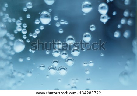 Bubbles of oxygen in glass of water on a blue background. Mineral water. Water enriched with oxygen.Oxygen. Water.Water background. Macro.Texture.Glass with water.Natural.
