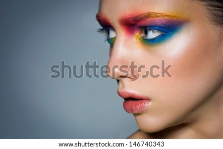 Close-up of beautiful female face with colorful make-up. Beauty. Fresh glowing skin. Space..Flower.Blue.Face art. Concept.