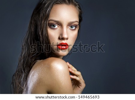 portrait of a young beauty girl with full red lips and perfect tanned wet skin. Shine make up space,studio