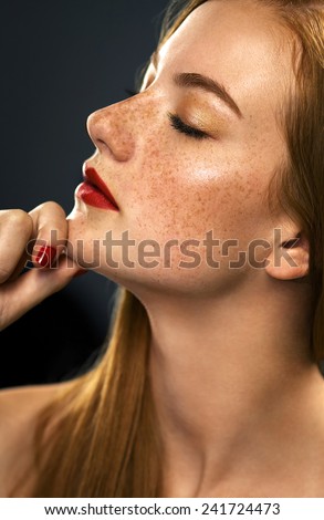 Beauty. Perfect skin.Red-haired model with freckles  on a black background in the studio  red lips pretty woman
