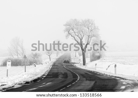 A Car pass by a Country road in Lorraine, between the snow covered fields