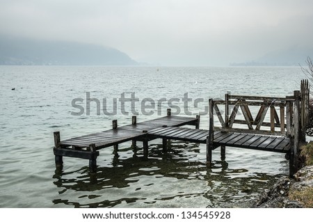 Wooden dock on the lake of Annecy, on a foggy day