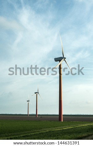 Wind power plant in the wheat fields by the highway at dusk in Netherlands