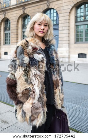 PARIS - JANUARY 23, 2014: Asian woman with blonde hairs wears a leather overcoat at the Place Vendome. Paris Fashion Week: Haute Couture 2014/2015 is held in Paris from January 20 to 23, 2014.