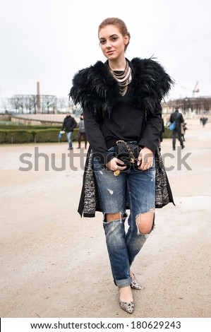 PARIS - MARCH 1, 2014: Stylish European woman with golden necklaces and ragged jeans in the Tuileries Garden. Paris Fashion Week: Ready to Wear 2014/2015 is held from February 25 to March 5, 2014.