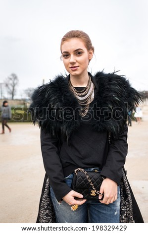 PARIS - MARCH 1, 2014: Stylish European woman with golden necklaces and ragged jeans in the Tuileries Garden. Paris is one of the capitals of fashion in the world.