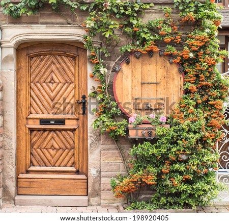 Wooden door decorated by Flowers and a wooden barrel, Itterswiller, Alsace
