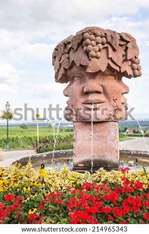 Fountain build with Sculpture of four faces and a hat with grapes in Alsace, France