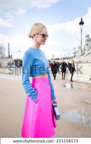 PARIS - MARCH 1, 2014: Stylish European woman with blue midriff and pink skirt in the Tuileries Garden. Paris Fashion Week: Ready to Wear 2014/2015 is held from February 25 to March 5, 2014.