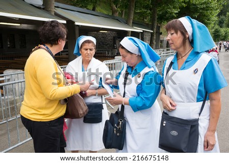 LOURDES, FRANCE - JULY 8, 2014: Nurses with blue shirt and white apron on the street.  The spring water from the grotto is believed by some to possess healing properties.