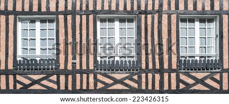 Closed windows of timber frame building with red brick texture wall in Beuvron en Auge, Nomandy, France