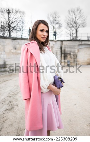 PARIS - MARCH 1, 2014: Stylish European woman with pink coat and pink skirt in the Tuileries Garden. Paris is one of the capitals of fashion in the world.