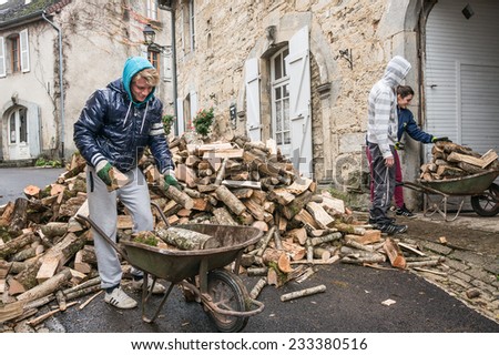 CHATEAU-CHALON, FRANCE -  NOVEMBER 11, 2014: Young people convey the firewood with a wheelbarrow into the house for the winter.