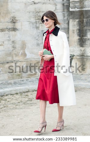 PARIS - MARCH 5, 2013: Stylish European woman with red skirt and white trench coat in the Tuileries Garden. Paris Fashion Week: Ready to Wear 2014/2015 is held from February 26 to March 6, 2013.