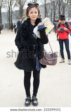 PARIS - MARS 5, 2013: Stylish Asian woman with black dress and Chanel bag in the Tuileries Garden. Paris Fashion Week: Ready to Wear 2013/2014 is held from February 26 to March 6, 2013.