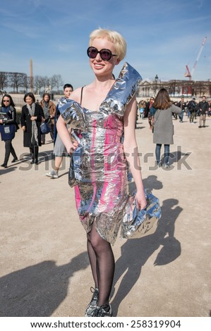PARIS, FRANCE - MARCH 6, 2015: Stylish european woman with silver paper clothes in the Tuileries Garden. Paris Fashion Week: Ready to Wear 2015/2016 is held from March 3 to 11, 2015.