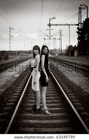 Two beautiful young woman posing on rails