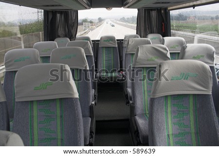 Empty seats with white headrest covers in a bus on freeway