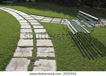 Lawn chairs on green grass in garden with curved walkway