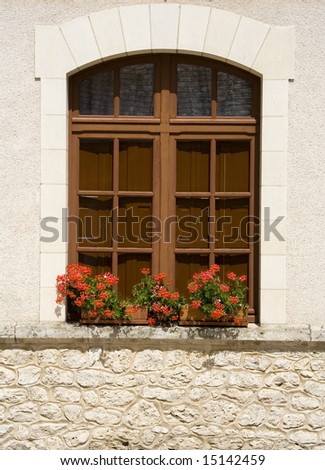 Red flowers in boxes in front of a window