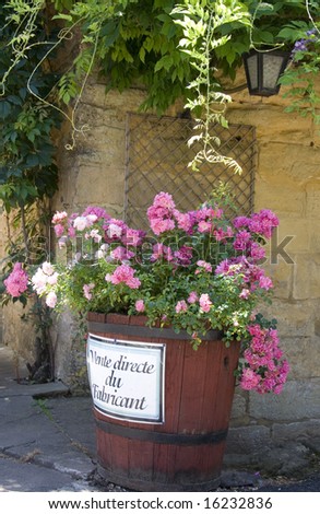 Large barrel filled with pink flowers with the words 'vente directe du fabricant' (direct sales) written on the side