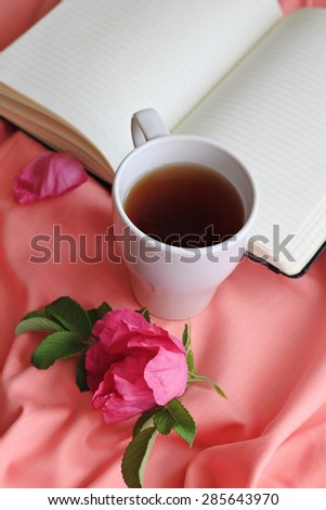 cup of herbal rose-hip tea breakfast in bed empty book