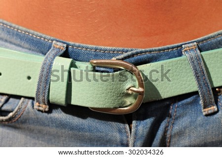 suntanned female belly fastened azure belt blue denim jeans slim young fit sunny close up background soft focus sensual accessories