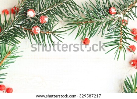 New Year wintry snowy decoration: new year branches and berries natural, white wooden backdrop, framed DIY christmas congratulation card.