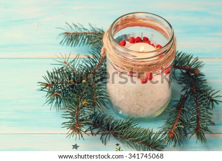 Handmade candle decor. Candle in glass jar, pine boughs, epsom salt, twine. Wooden blue background. Toned.