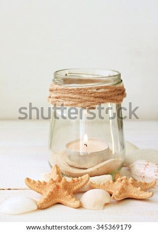 Votive tea light candles  in jars with sea sand, sea shells. Marine style home accessories for beach themed interior decorating