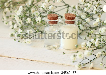 Glass vials with skincare cosmetic product, flower background. Botanical cream and tonic