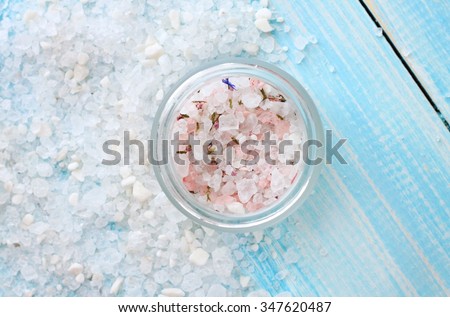 Herbal sea salt scattered, aromatic herbs in jar, on wooden table