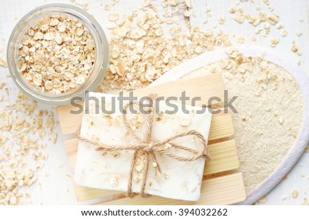 Oatmeal flakes skin care treatment. Rolled oats scattered, body scrubber, handmade soap bar.