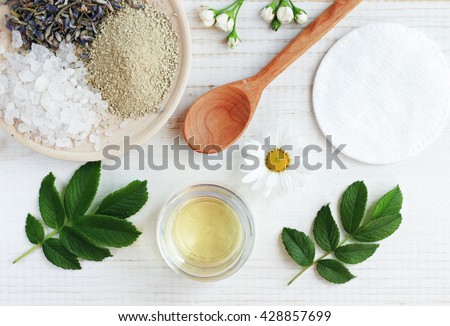 Natural herbal skin care products, top view ingredients. Cosmetic oil, clay, sea salt, herbs, plant leaves. Facial treatment preparation background.